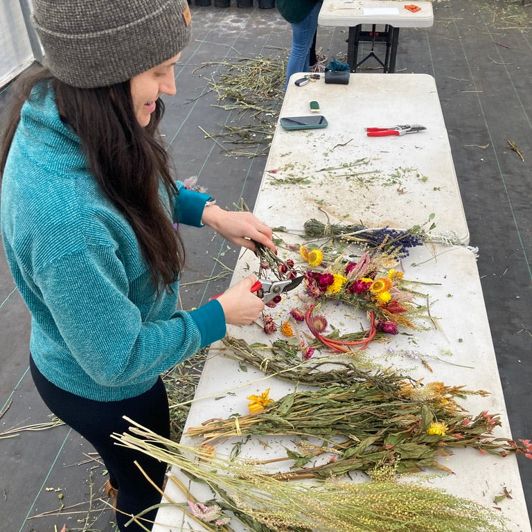 Person working with dried flowers and plants on a table outdoors