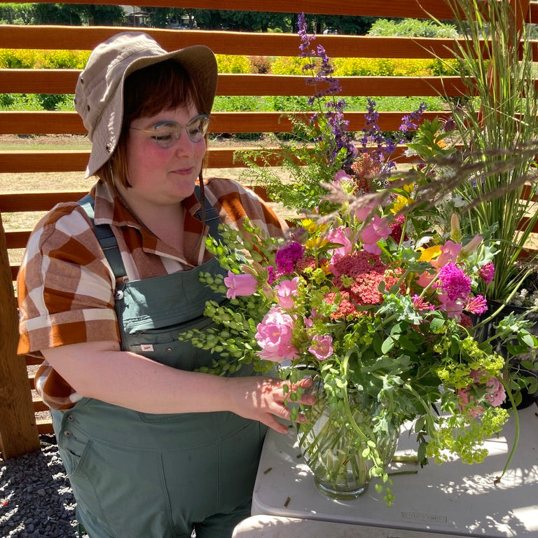 Person arranging a bouquet of flowers in a garden setting