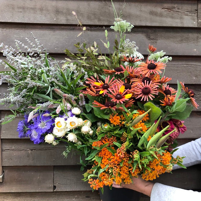 Person holding a bouquet of flowers against a wooden wall
